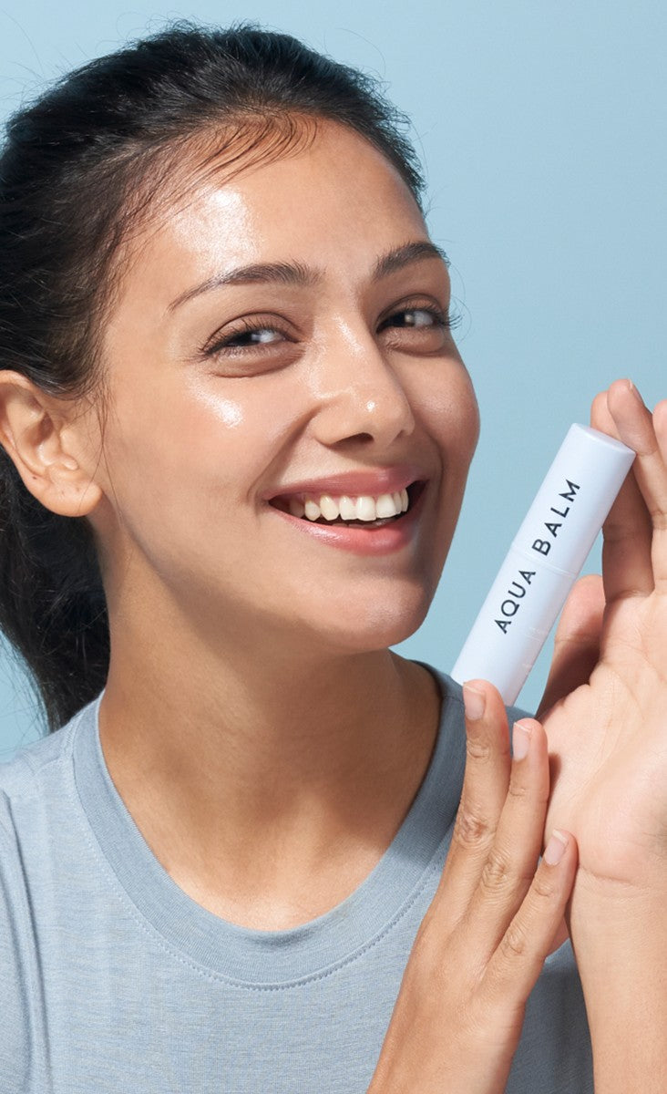 Smiling woman holding the KAHI Aqua Balm stick