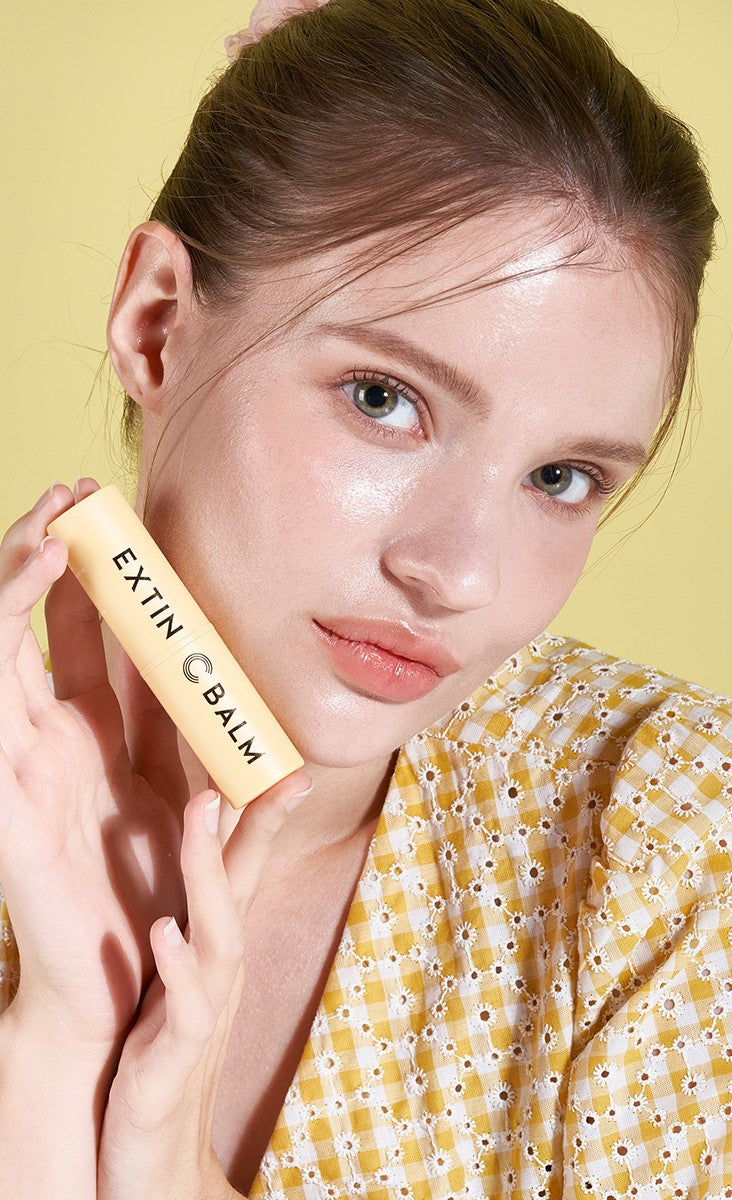 Woman holding the KAHI Extin C Balm stick against her cheek