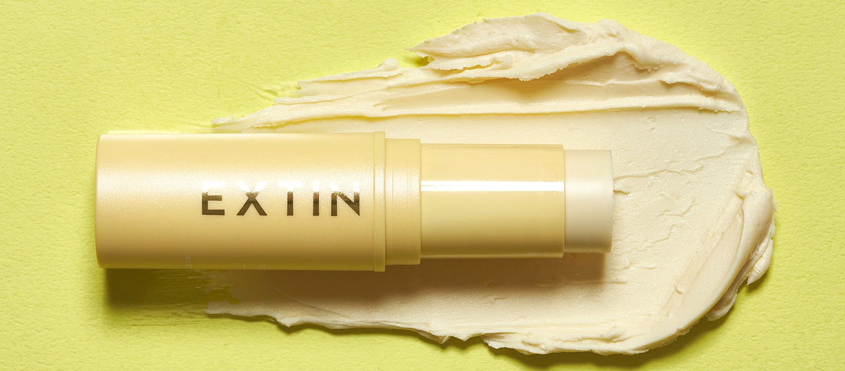 KAHI Extin C Balm stick lying on a creamy swatch of the vitamin C balm
